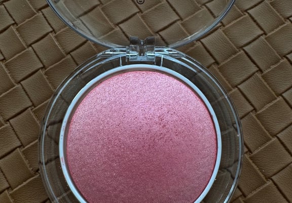 Round compact with clear lid showing a shimmery pink powder blush inside. review