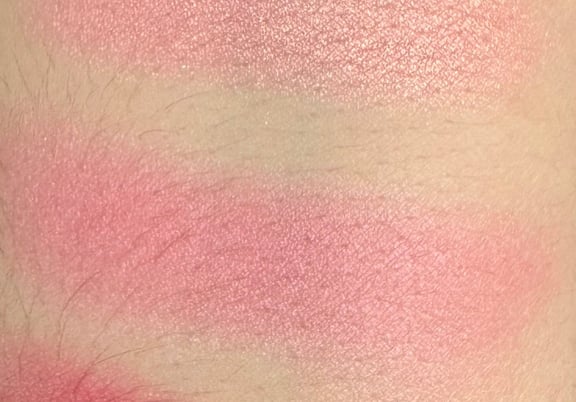 Swatches of shimmery blush shades in pink, coral, and rose tones applied on skin. review