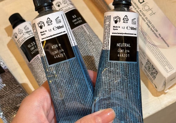 Multiple tubes of L'Oréal Professionnel Dia Light hair color in ash and neutral shades held in hand. review