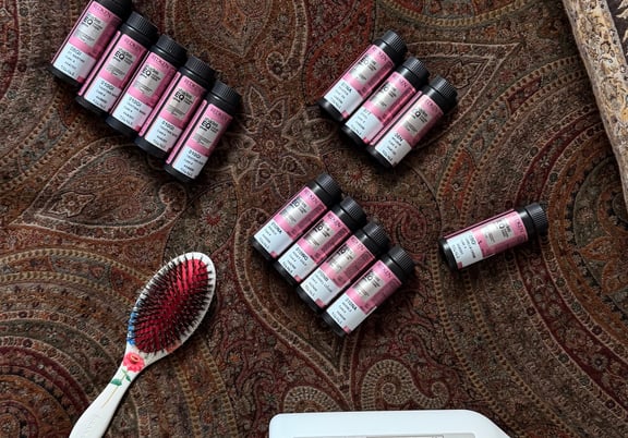 Multiple bottles of Redken Shades EQ hair color, a large Redken gloss bottle, and a floral hairbrush on a patterned fabric. review