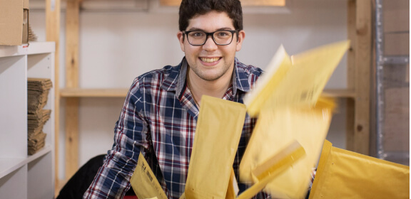 Un miembro del equipo de logística sonríe en medio de unos paquetes.